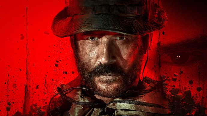 A bearded and grizzled soldier with a bucket hat on looks, with a steely eye glare, at the camera.