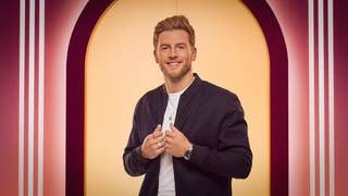 A photograph showing the upper half of a smartly turned out young man with a charming smile. It's Kieran from Love is Blind UK season two.